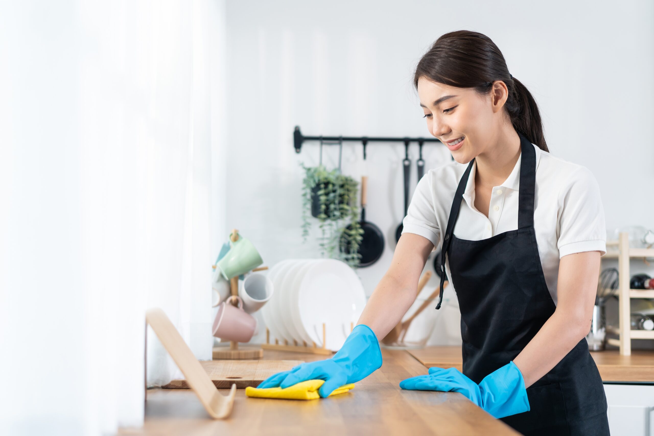 Lady cleaning table surface with yellow wipe